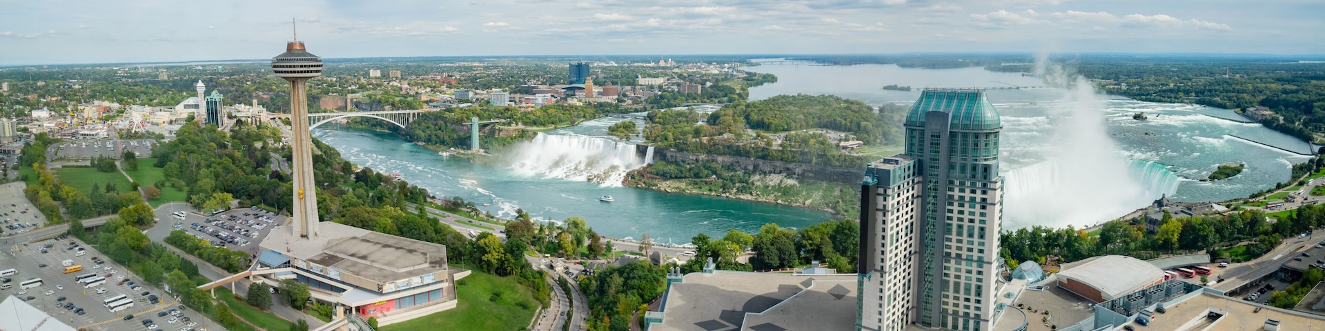 Eine Stadtansicht mit einem markanten Turm, einem großen Wasserfall und einem Fluss.