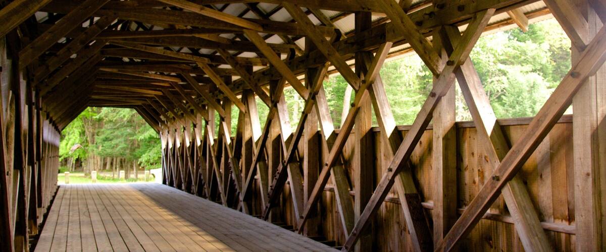 A covered wooden walkway with a wooden floor and a metal roof structure.