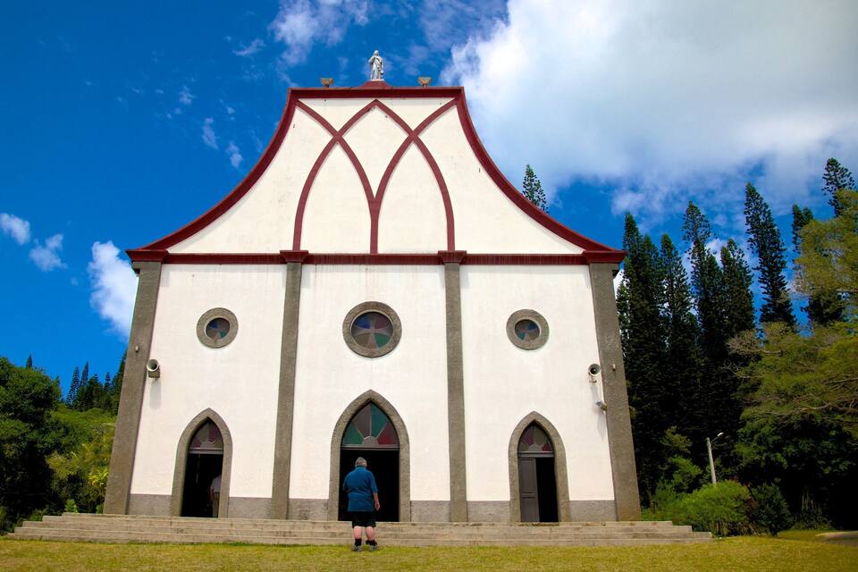 A church with a white facade, red roof, and three arched windows.