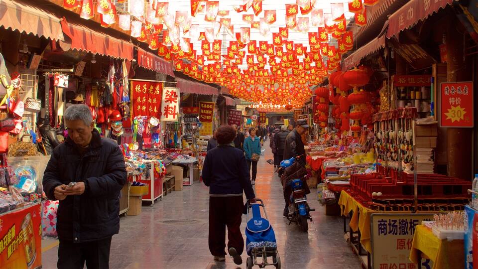 Un mercado animado con faroles rojos y varios puestos que ofrecen productos.