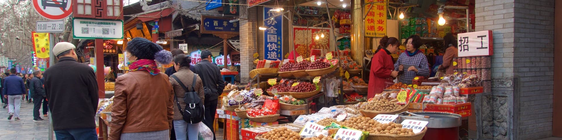 A bustling street market with various stalls selling fruits, nuts, and other goods.