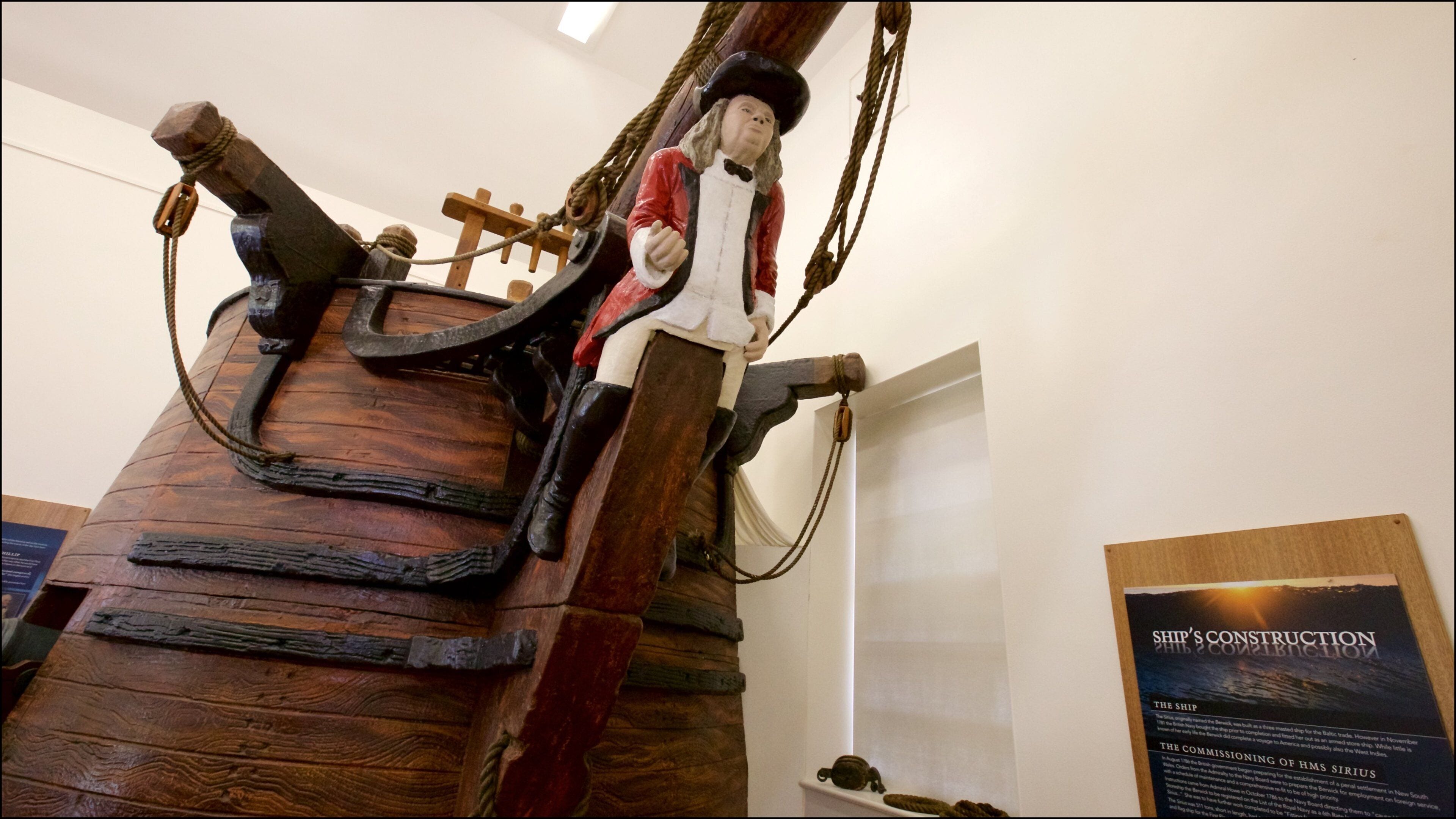 Um leme de navio e uma figura vestida com traje histórico.