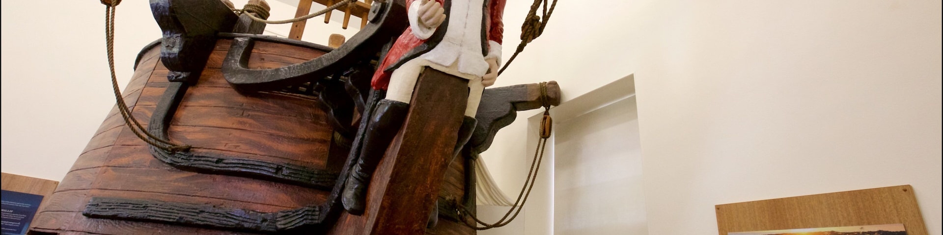 Um leme de navio e uma figura vestida com traje histórico.