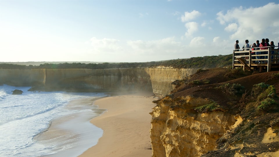 A coastal cliff with a sandy beach and a viewing platform with people.