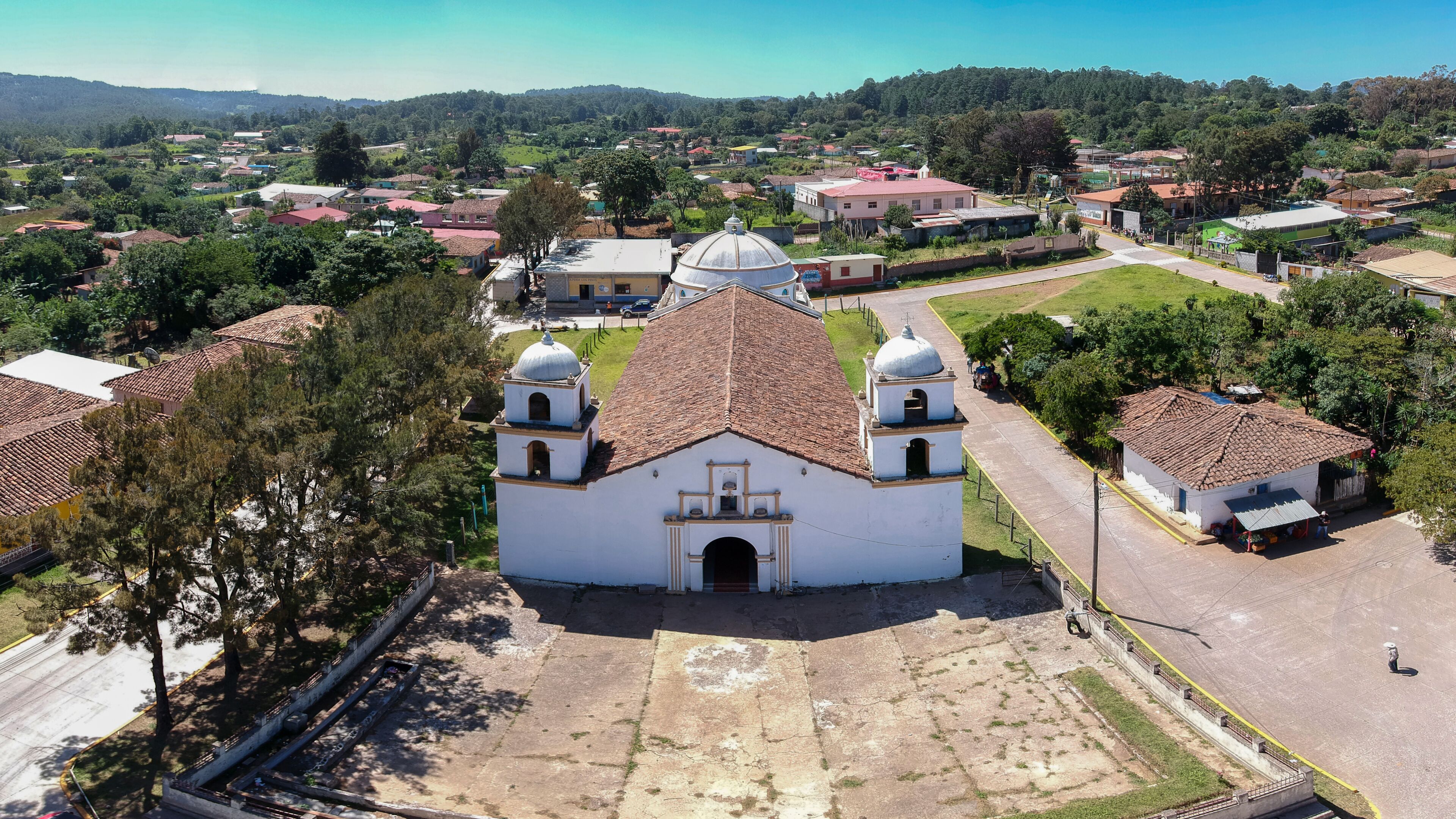 A white church with a dome and bell towers, surrounded by residential buildings and greenery.