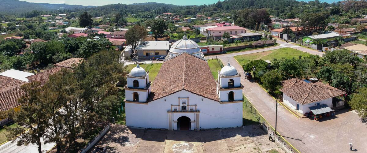 A white church with a dome and bell towers, surrounded by residential buildings and greenery.