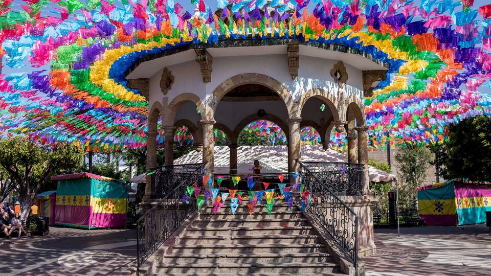 A historic building with colorful flags and a staircase leading up to it.
