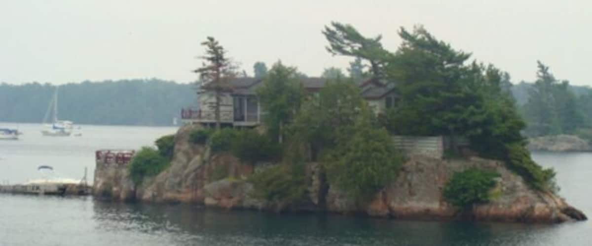 A small island with a house surrounded by trees and a body of water.