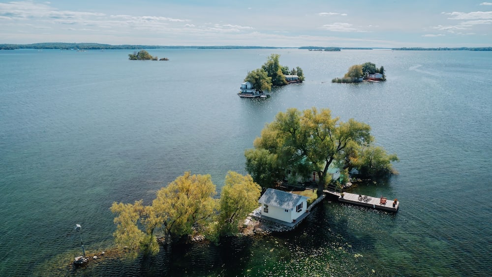 Un lac parsemé de plusieurs petites îles, dont une avec un quai et une maison, et une autre avec un bateau.