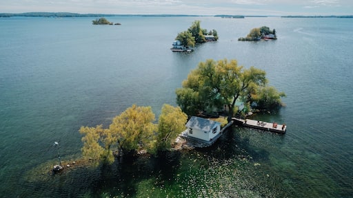 Un lac parsemé de plusieurs petites îles, dont une avec un quai et une maison, et une autre avec un bateau.