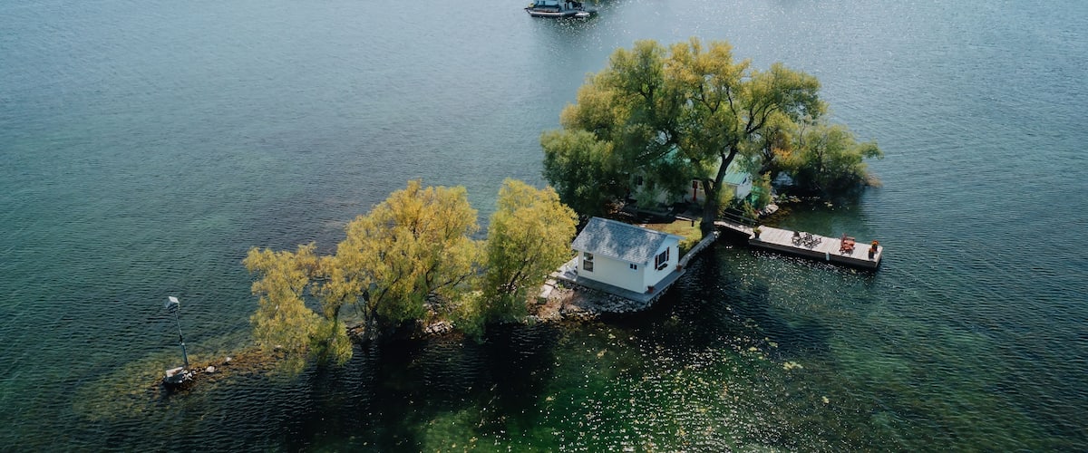 A lake with several small islands, one with a dock and a house, and another with a boat.