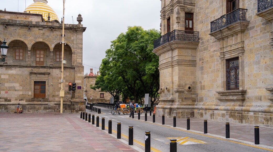 Dos hombres van con sus bicicletas y sus mercancías por la calle Morelos del centro histórico de Guadalajara.