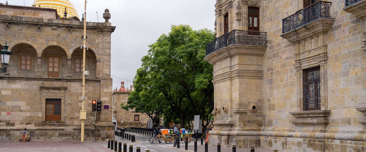 Dos hombres van con sus bicicletas y sus mercancías por la calle Morelos del centro histórico de Guadalajara.