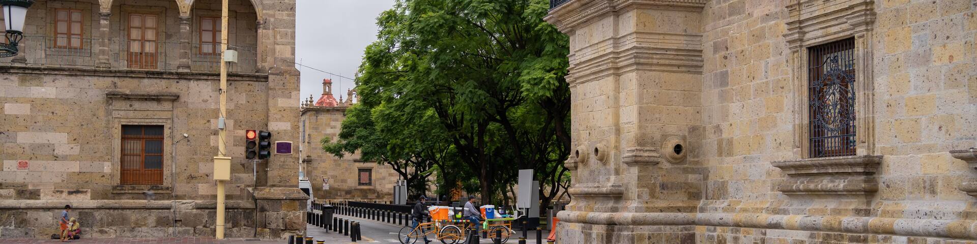 Dos hombres van con sus bicicletas y sus mercancías por la calle Morelos del centro histórico de Guadalajara.