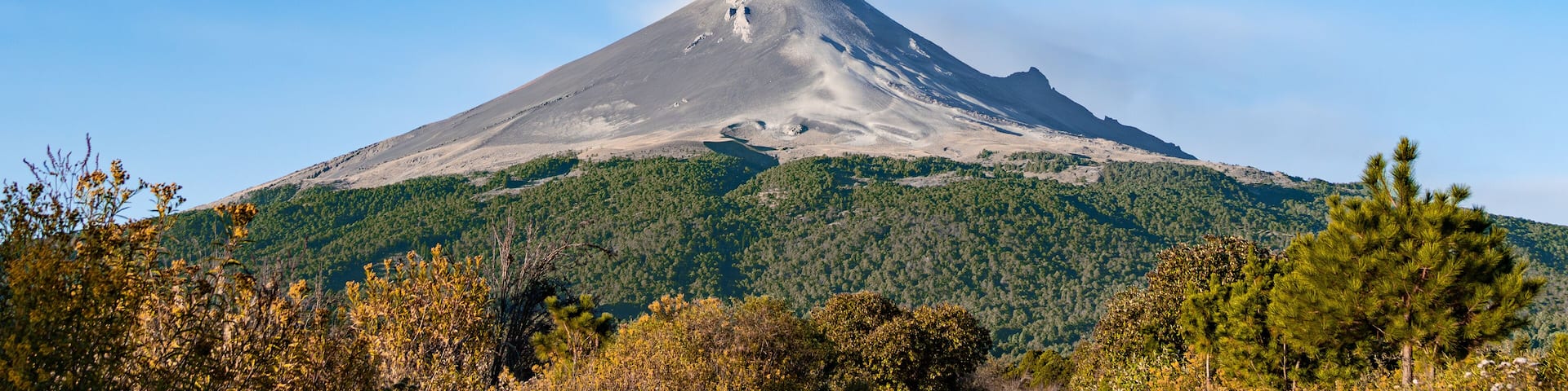 A mountain with a cloud of smoke rising from it. popocatepetl volcano mexico,