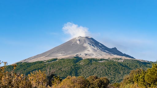 A mountain with a cloud of smoke rising from it. popocatepetl volcano mexico,