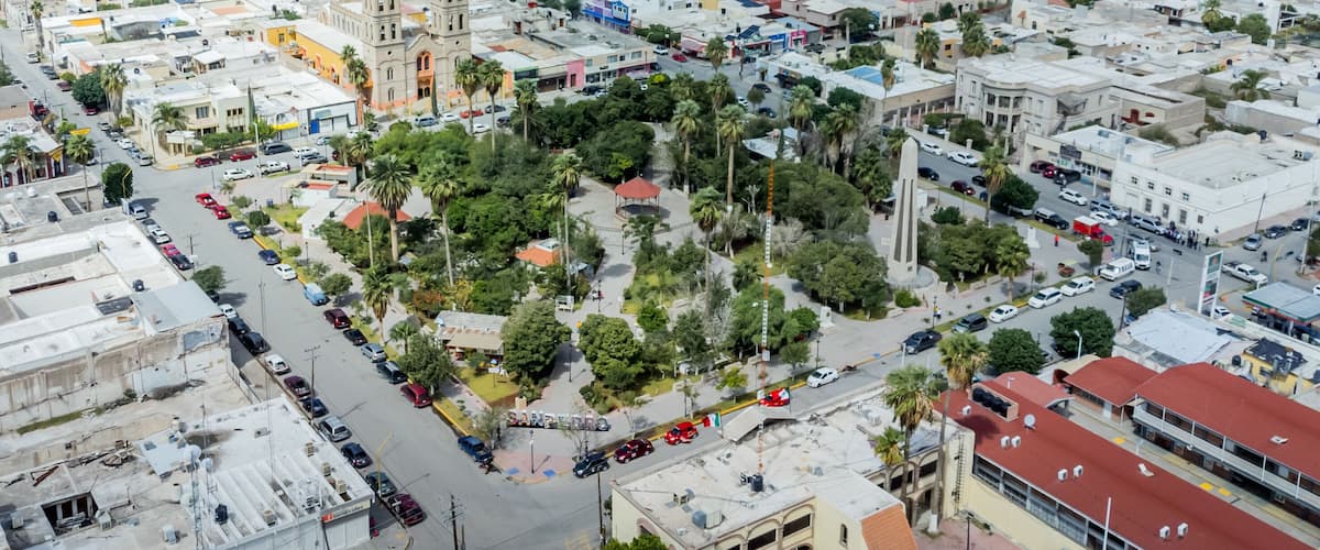 A densely populated urban area with a prominent church featuring two towers, surrounded by palm trees and various buildings.