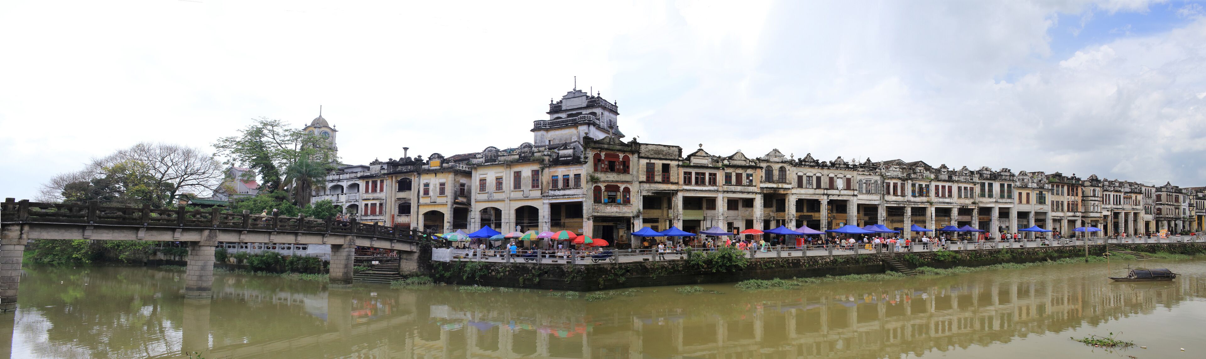 A historic riverside building with a bridge and a boat.
