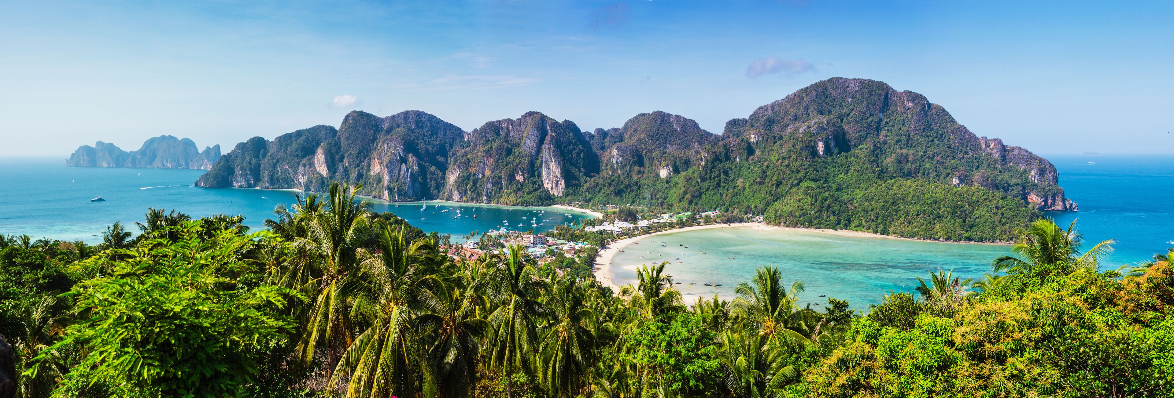 A coastal landscape with a beach, clear turquoise waters, and a line of limestone cliffs.