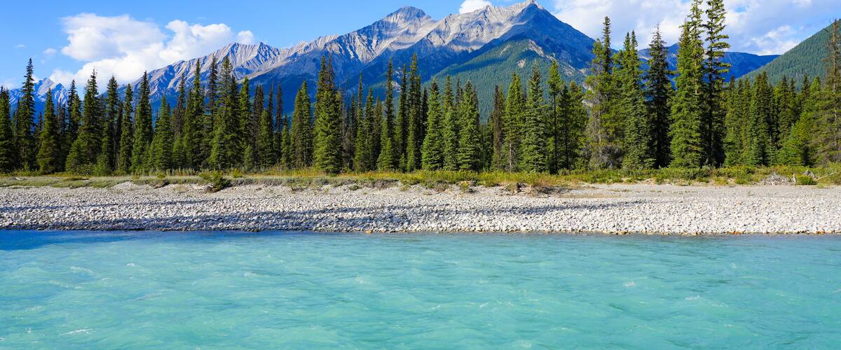 A mountain range with clear turquoise waters in the foreground.