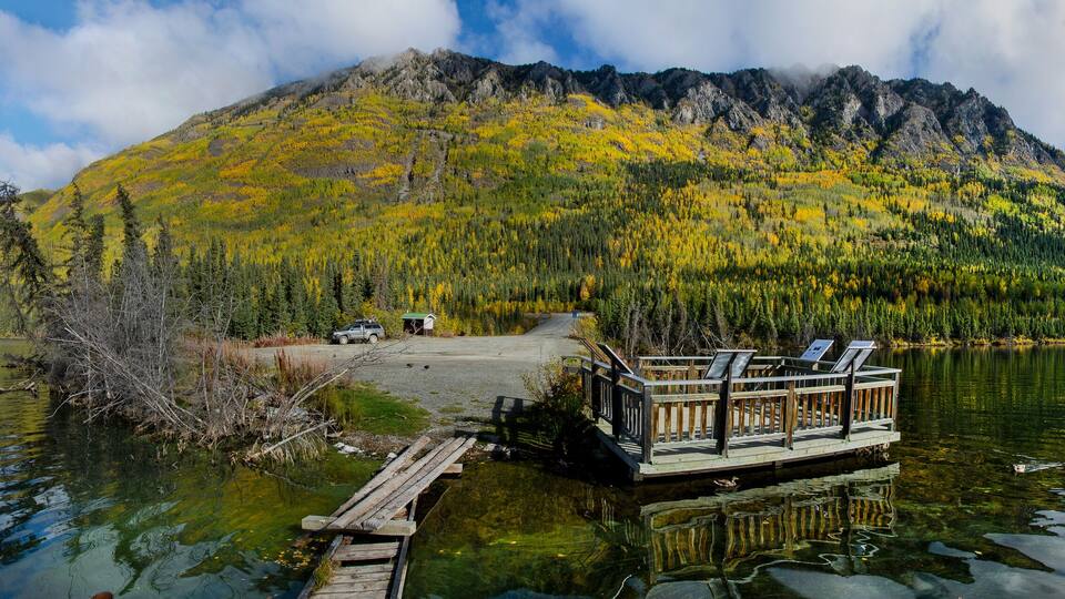 A lake with a dock and a mountain in the background.