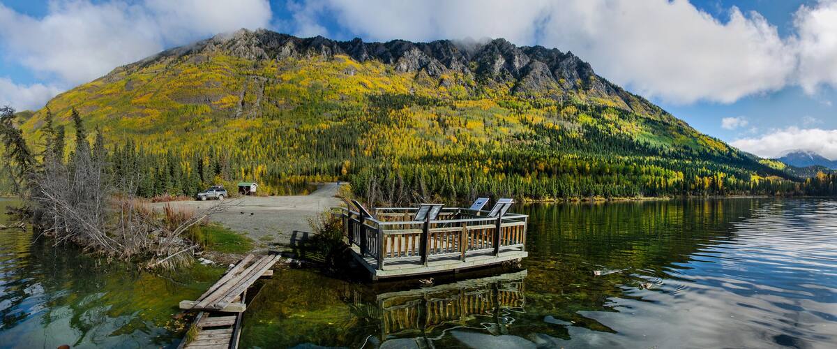 A lake with a dock and a mountain in the background.