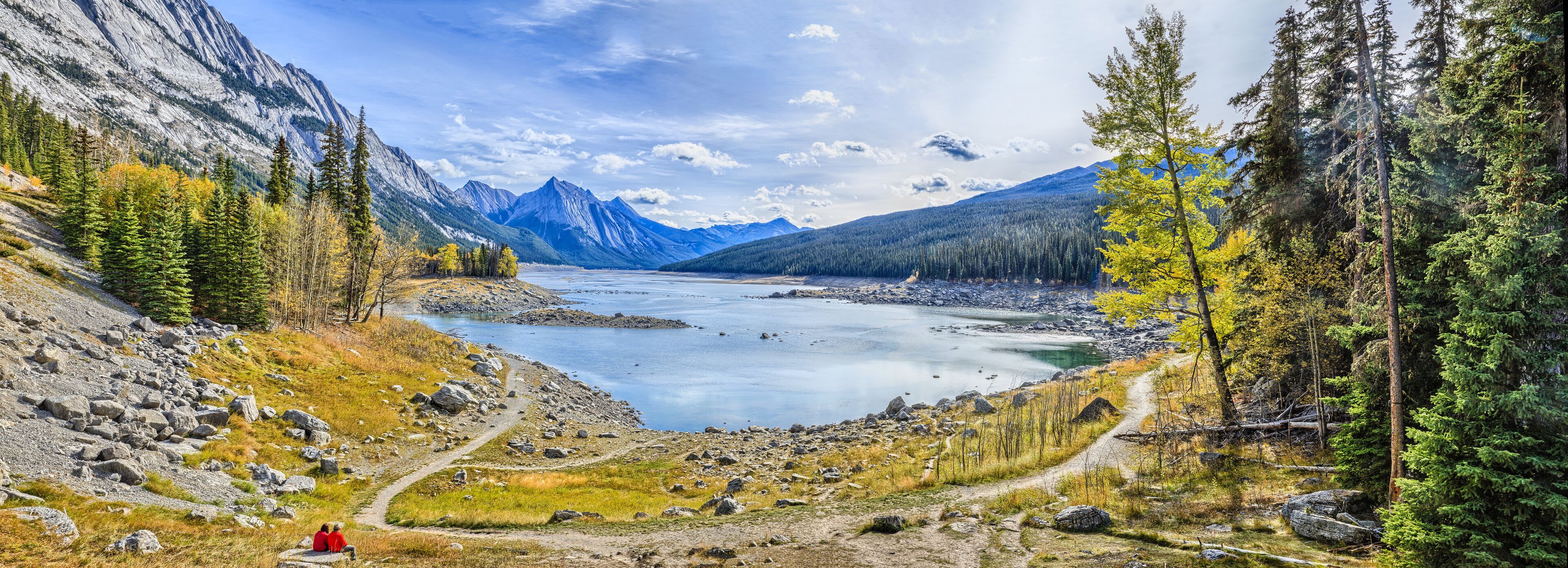A mountainous landscape with a lake, rocky terrain, and coniferous trees.