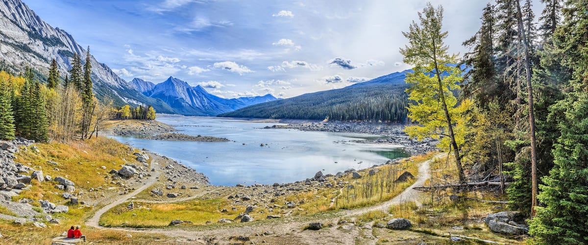 A mountainous landscape with a lake, rocky terrain, and coniferous trees.