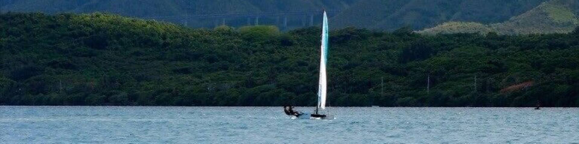 Un velero en aguas turquesas con una montaña al fondo.