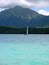 Un velero en aguas turquesas con una montaña al fondo.