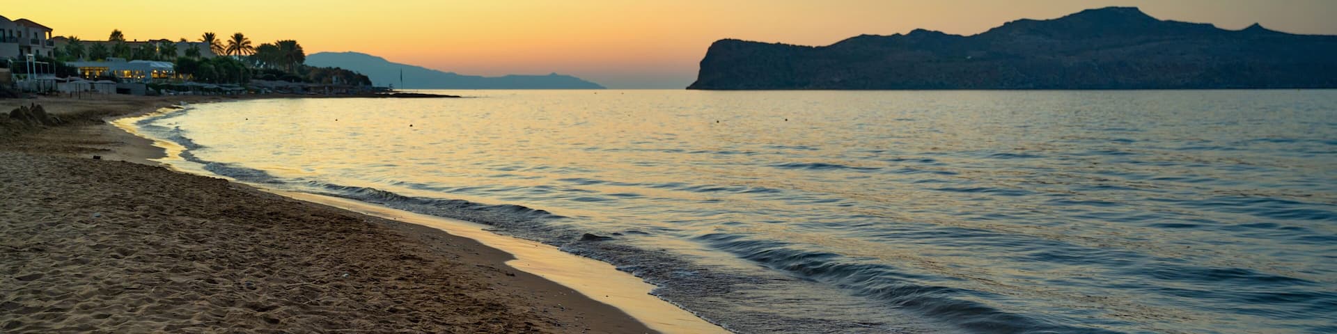 Evening illumination of sky, empty beach, sea and island of St. Theodora in Kato Stalos, Crete.