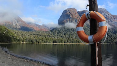 Un flotador sujeto a un poste de madera junto a un lago con montañas al fondo.