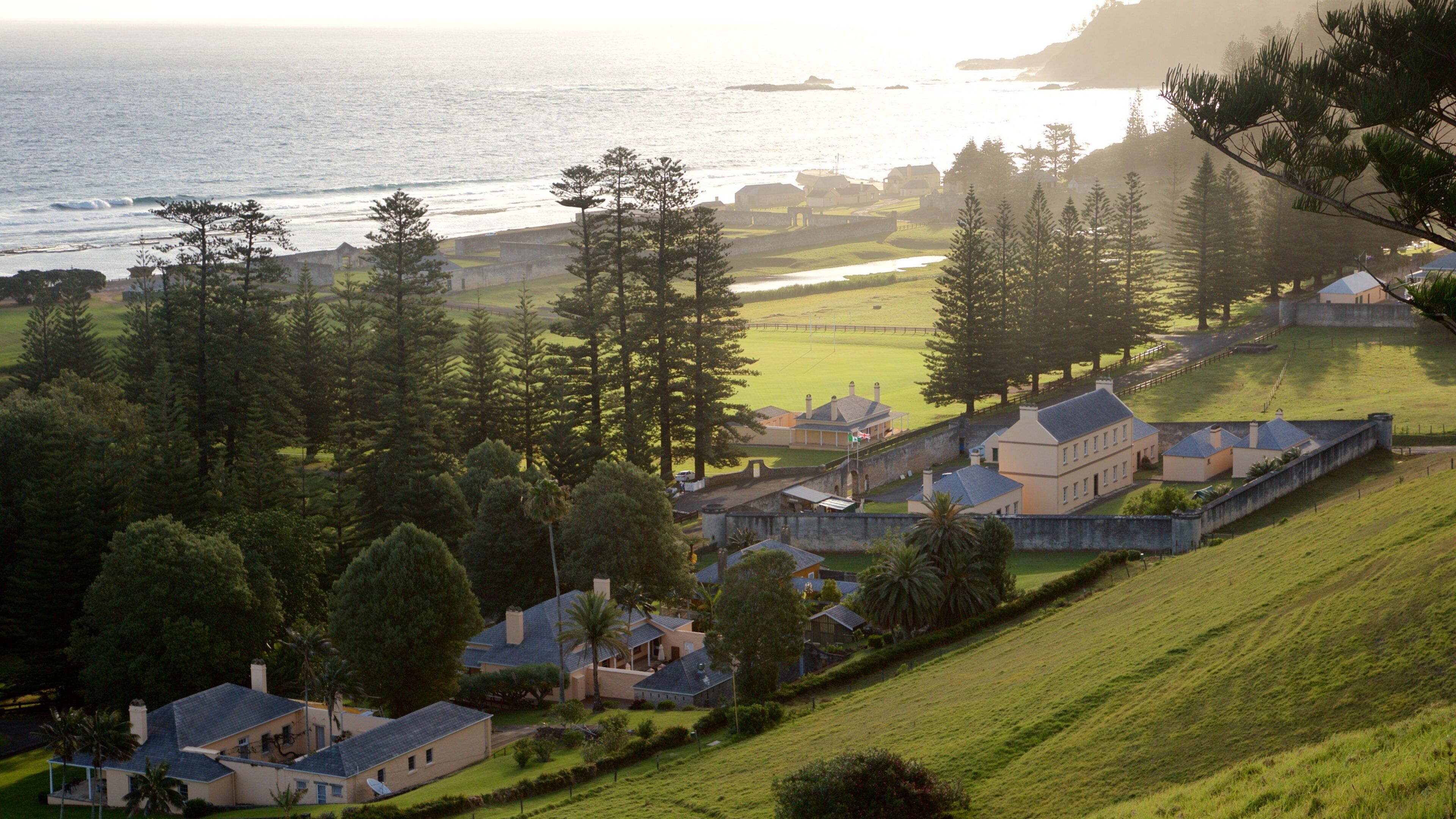 Norfolkøya fasiliteter samt liten by eller landsby, kyst og solnedgang