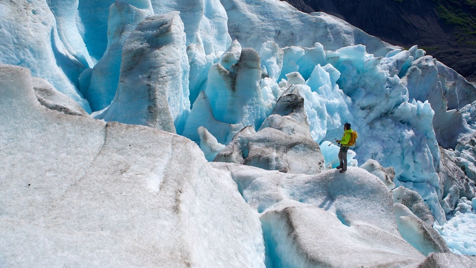 A glacier with a climber in a yellow jacket.