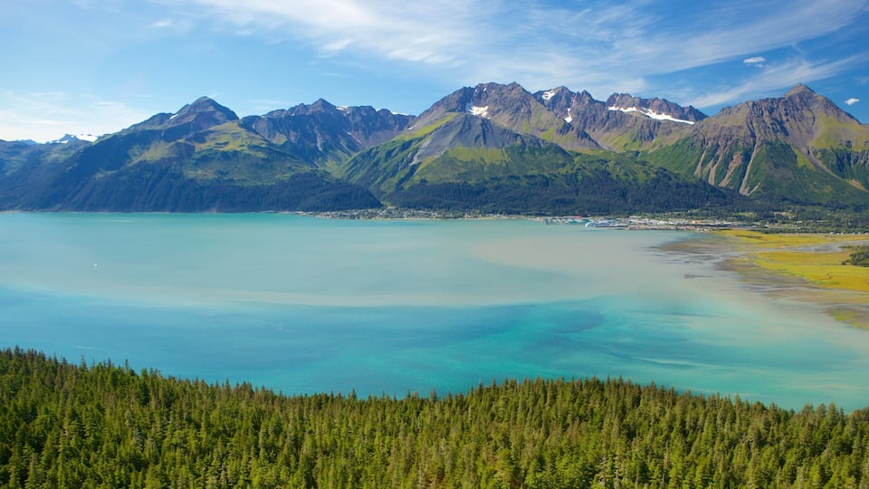 A mountain range with a clear lake and dense forest.