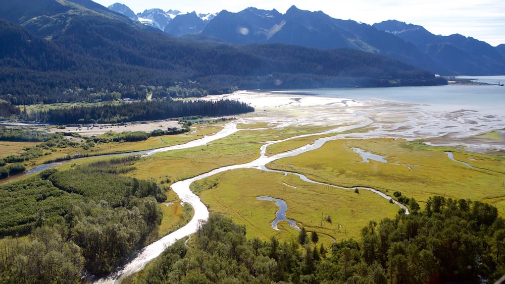 Une rivière serpente à travers une vallée, avec des montagnes en arrière-plan.