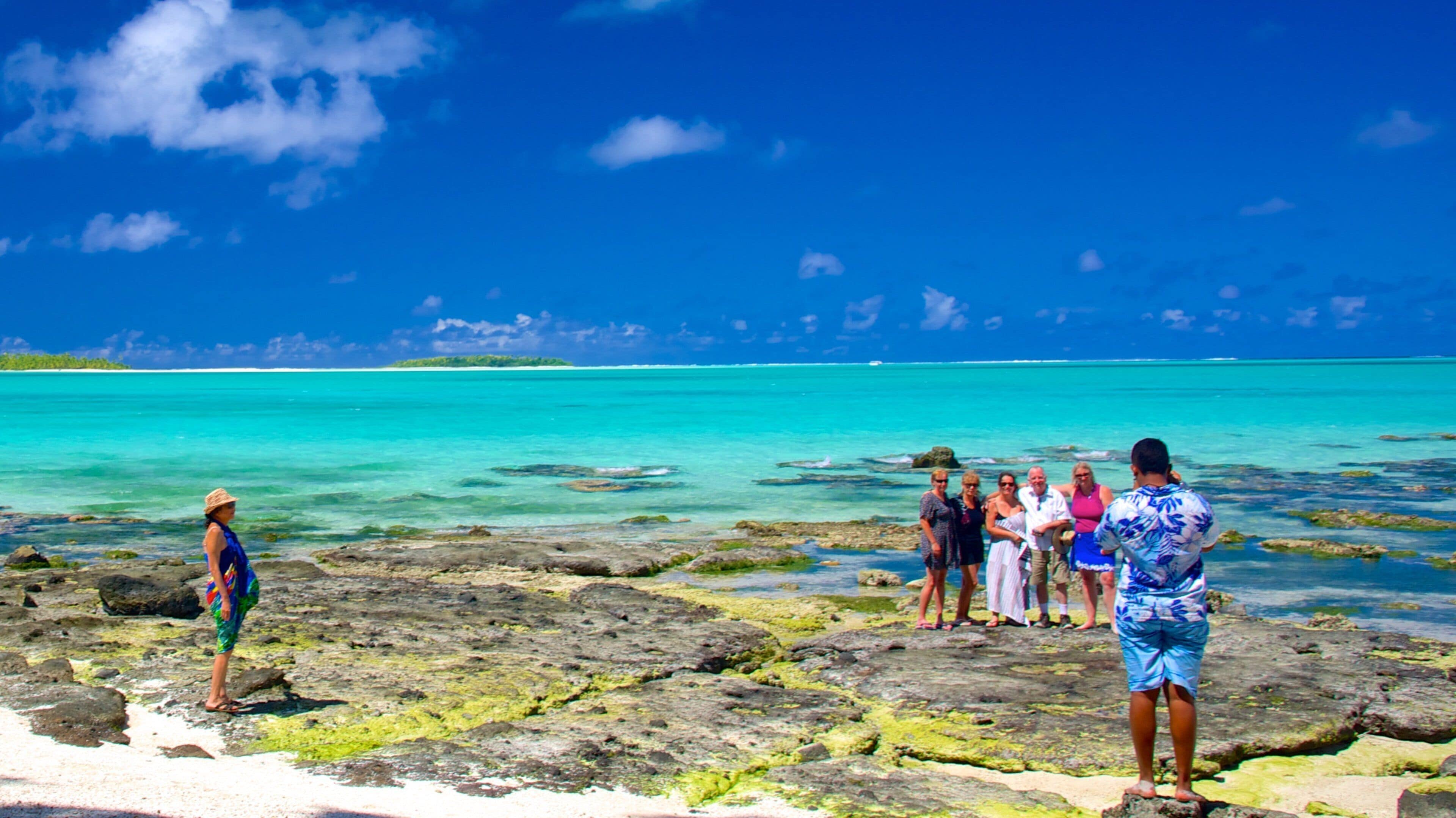 Aitutaki featuring general coastal views as well as a small group of people