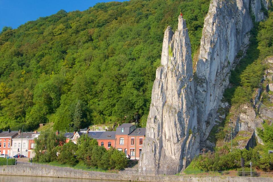 A rocky cliff with a flag, houses, and a river.