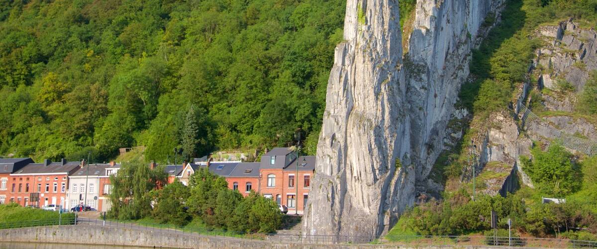 A rocky cliff with a flag, houses, and a river.