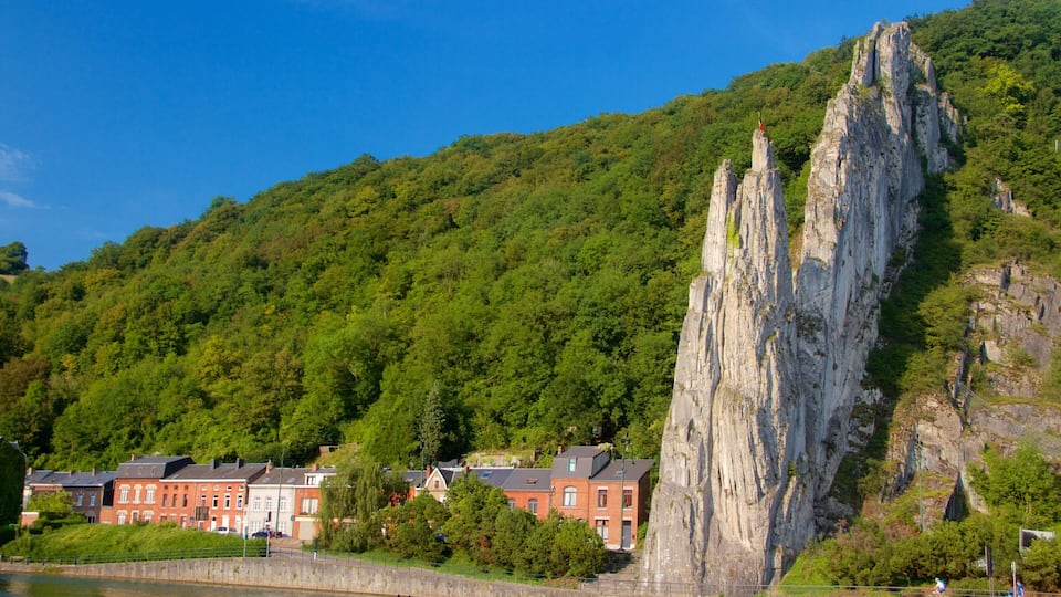 A rocky cliff, a river, and red buildings on a hillside.
