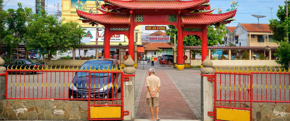 A traditional red gate with ornate decorations, leading to a building with a sign reading "HOK AN KIONG".
