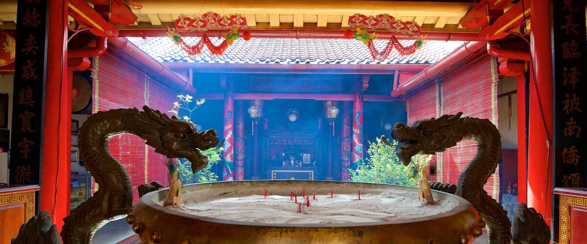 A traditional Chinese altar with two dragon statues, incense burners, and red decorations.