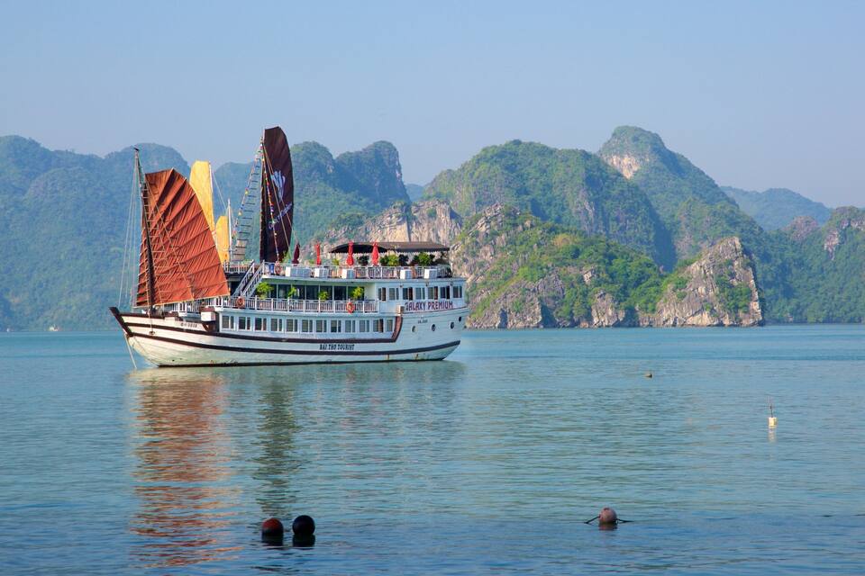 A boat named Galaxy Premium on calm waters with a mountainous backdrop.