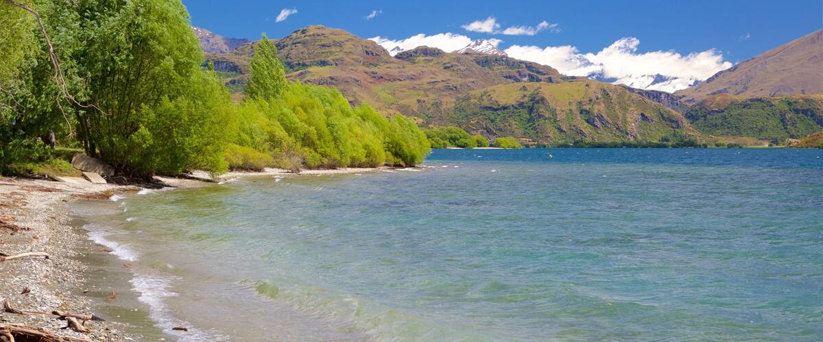 A clear lake surrounded by green hills and mountains.