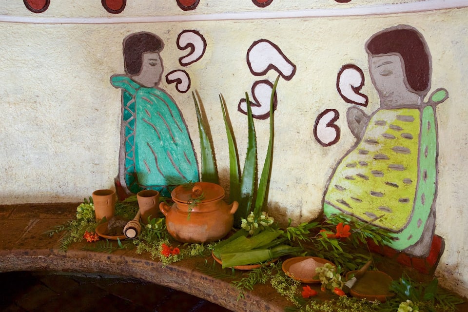 A mural with two figures, a table with pottery, and plants.