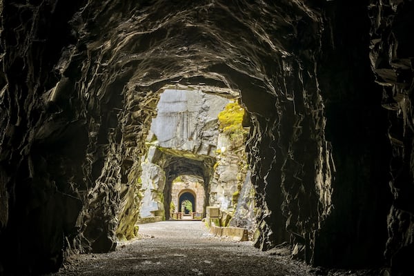 L’entrée d’une grotte, surmontée d’un arc en pierre, mène à un sentier.