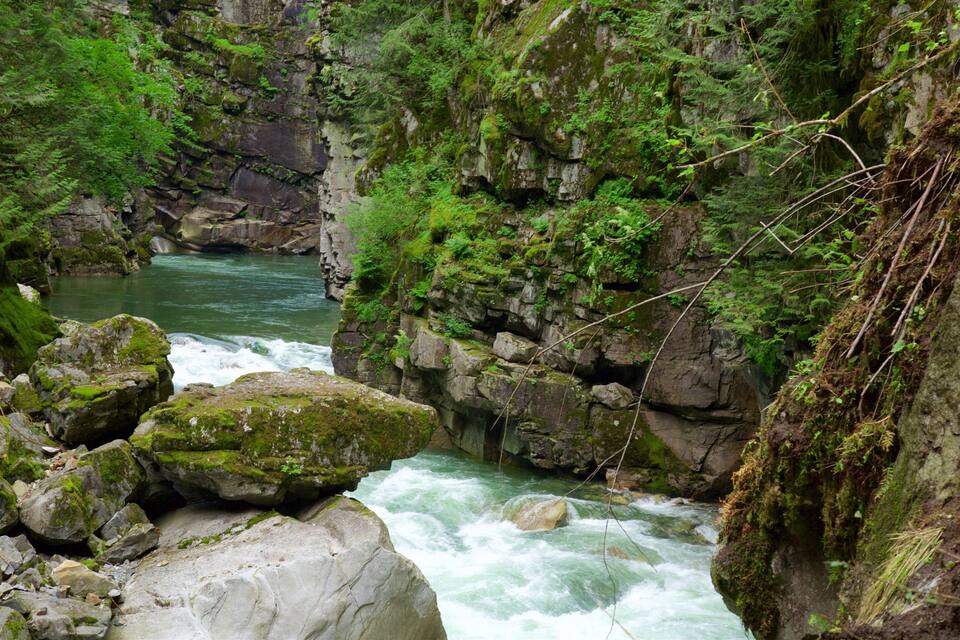 A fast-flowing river surrounded by rocky cliffs and lush greenery.