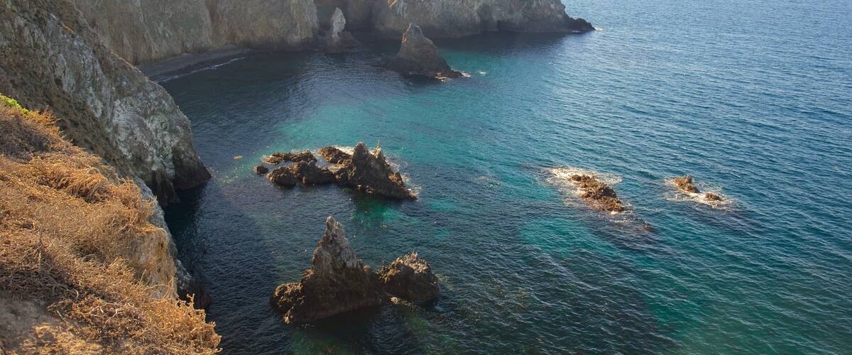 A coastal landscape with rocky cliffs and clear blue waters.