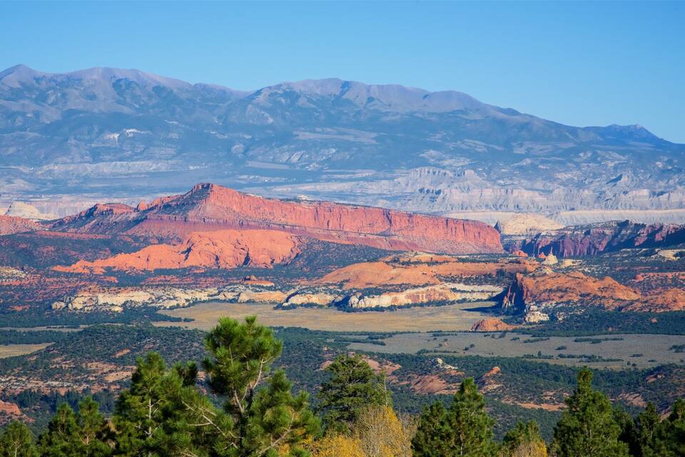 A mountainous landscape with red rock formations and green vegetation.