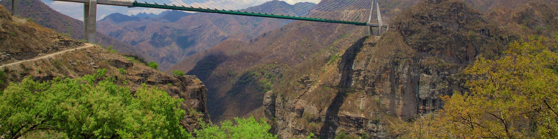A suspension bridge over a canyon with mountains in the background.